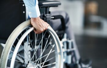 Wheelchair, disability and man hand holding wheel in a hospital for healthcare. Disabled, mobility problem and male person in a clinic for support and medical care with hands of patient and mockup